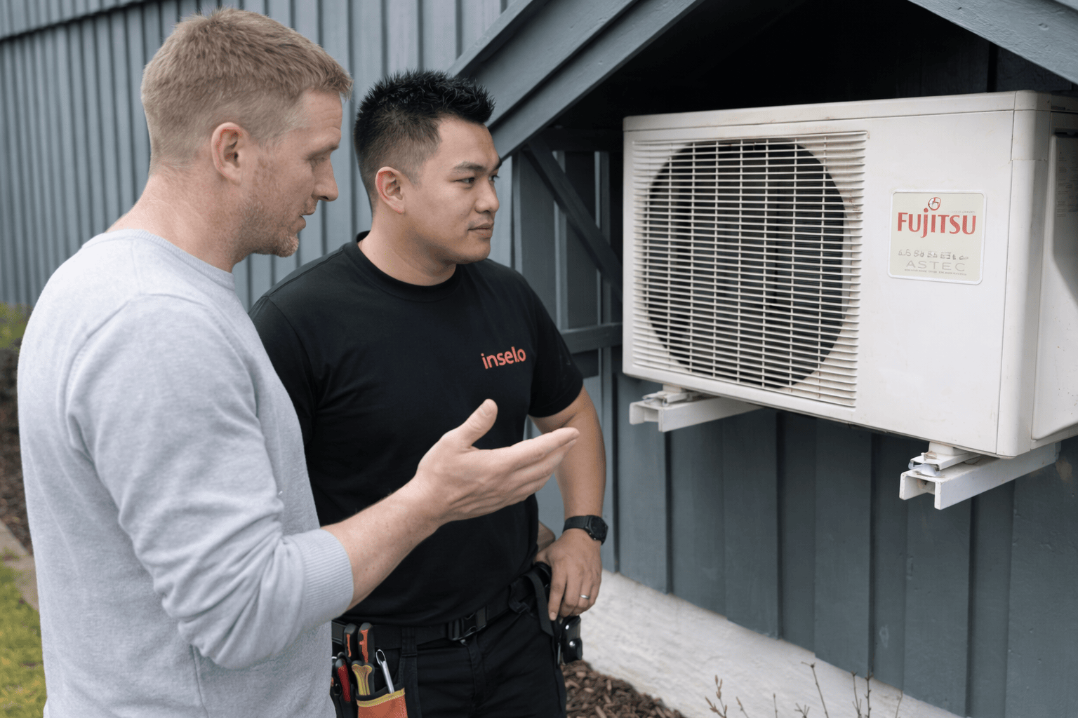 Kund diskuterar med tekniker kring luftvärmepumpen på baksidan huset